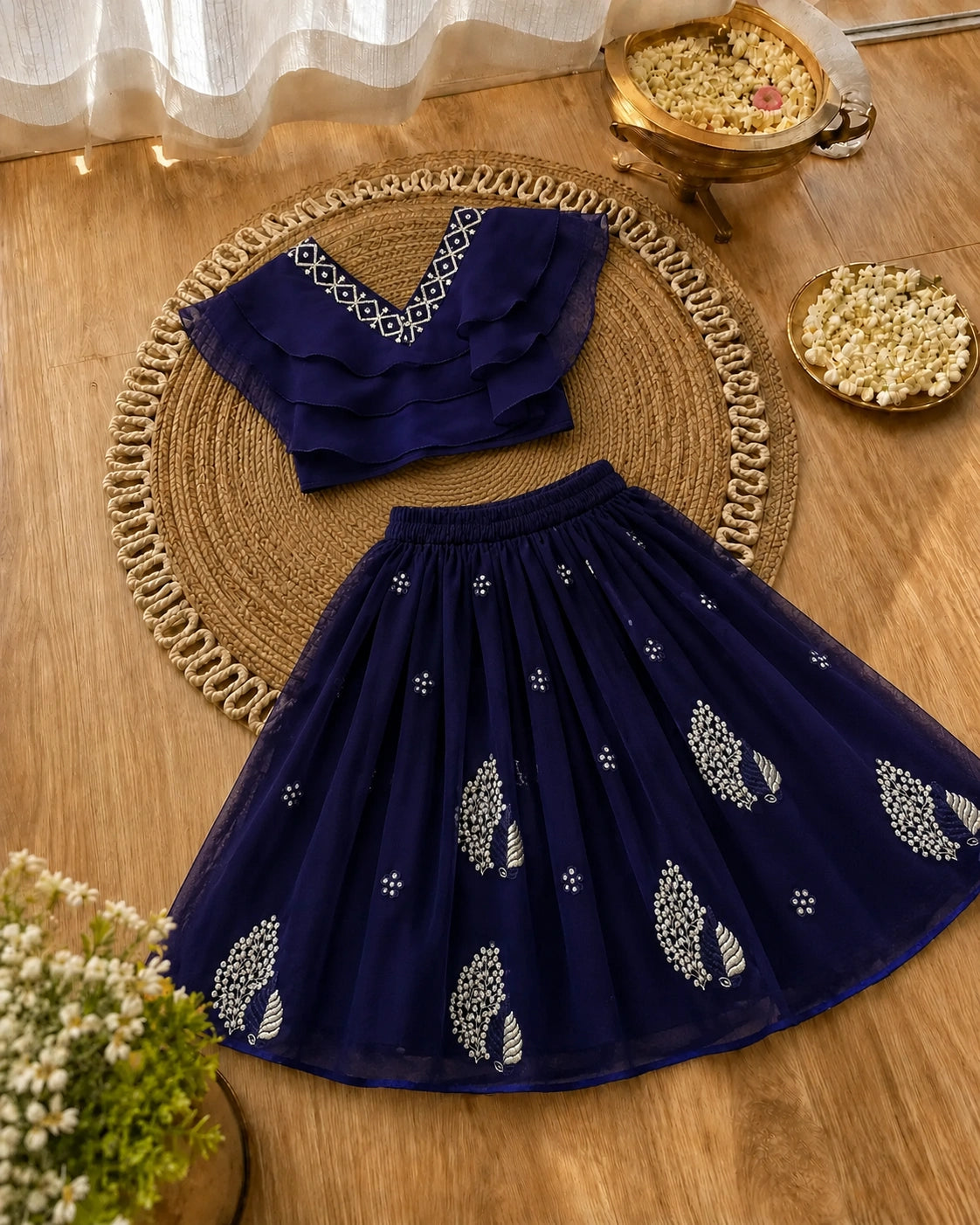 Navy blue embroidered top and skirt set on a wooden surface with decorative elements.