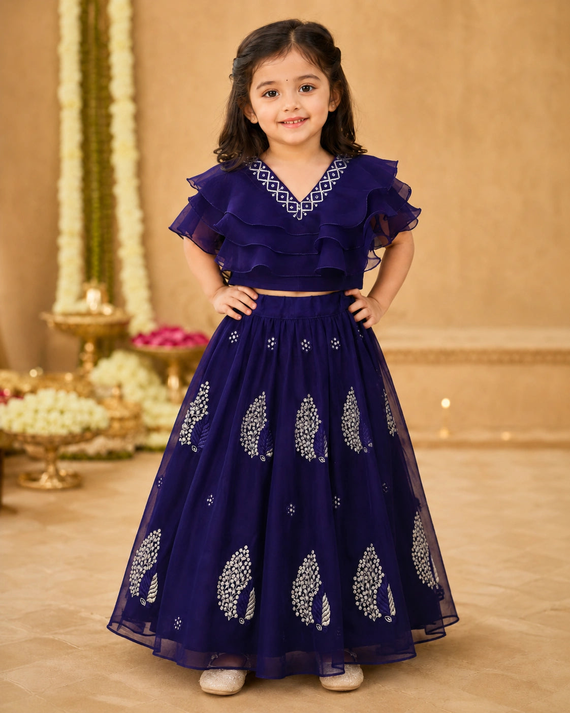 Young girl in a dark blue traditional outfit with white patterns on a decorated indoor background