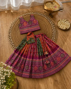 Colorful traditional outfit with a top and skirt on a woven mat, surrounded by decorative items on a wooden surface.