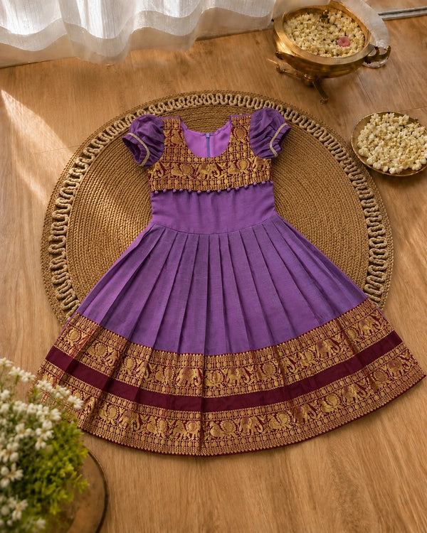 Purple and gold traditional dress on a woven mat with decorative elements.