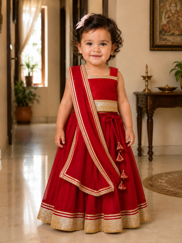 Child wearing a red traditional outfit with gold details in an indoor setting.
